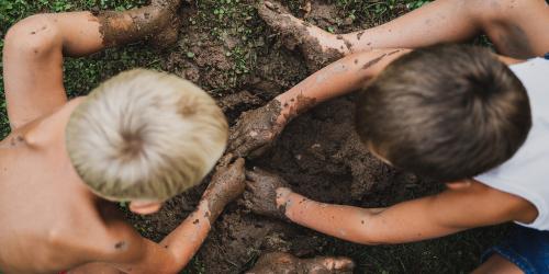 Two boys digging in the mud