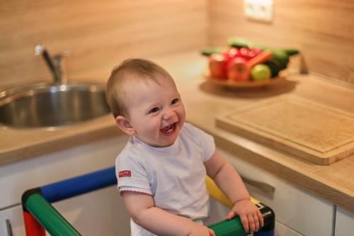 Child standing on learning tower and grinning