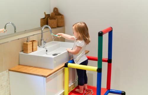 Girl on learning tower brushing teeth