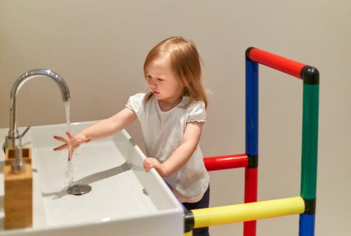 Dziewczynka myje ręce, korzystając z wieży do nauki